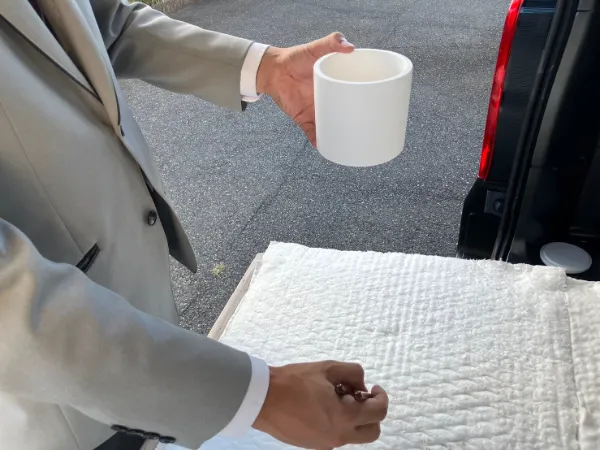 白いマグカップを持つグレーのスーツを着た男性の手元