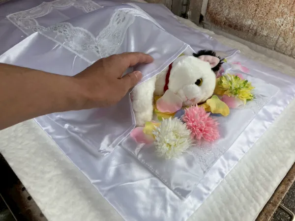 白いぬいぐるみと黄色とピンク色の造花が透明な包装で包まれたギフト